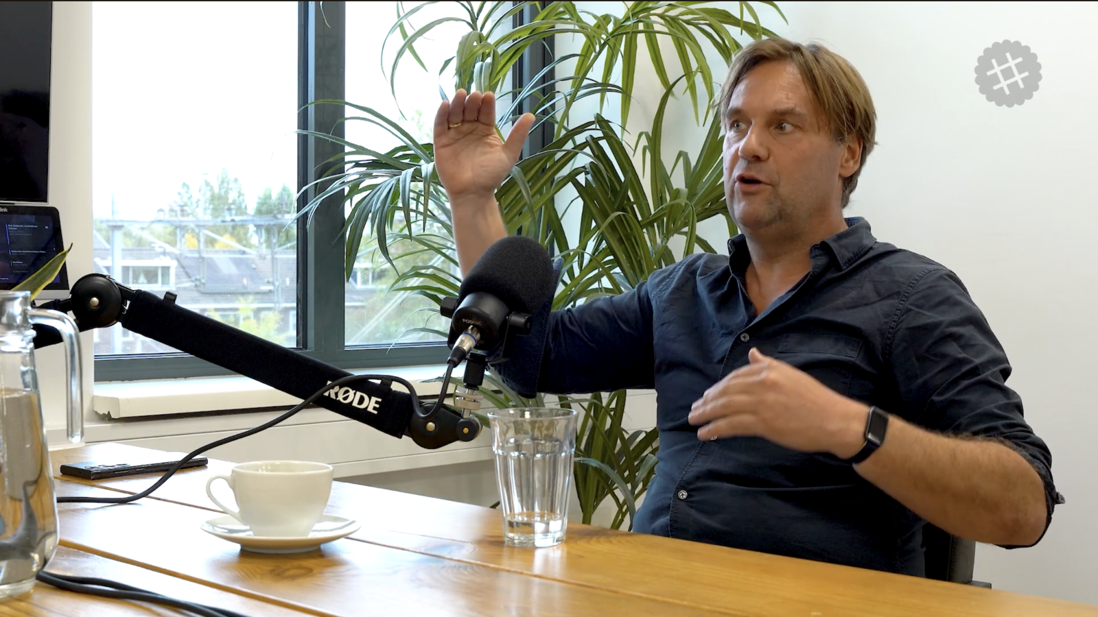 Arnout Hellemans talking, mid-gesture, recording with a Rode podcast microphone